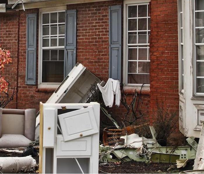damaged furniture and other items outside a brick home